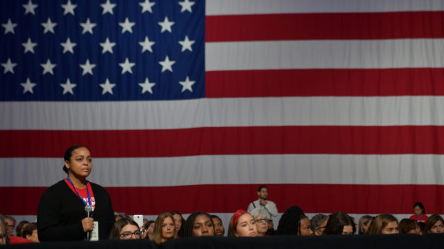 A survivor of gun violence stands in front of an American flag