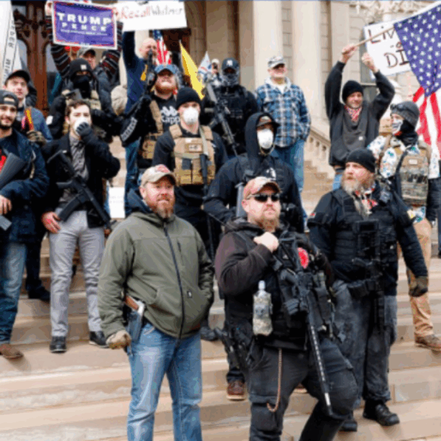 Armed protestors stand in a group on the steps of a building