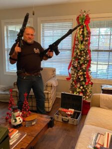 Kevin Greeson posing with guns in front of a Christmas tree