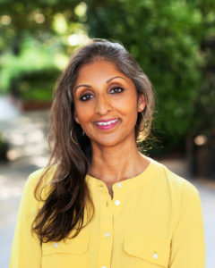 Dr. Sonali Rajan smiling and wearing a yellow shirt