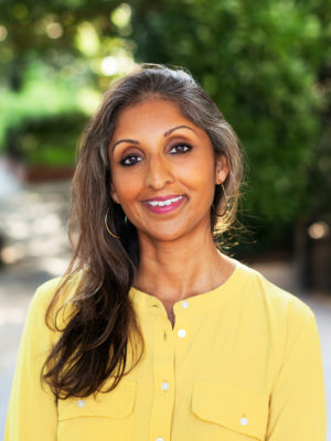 Dr. Sonali Rajan smiling and wearing a yellow shirt
