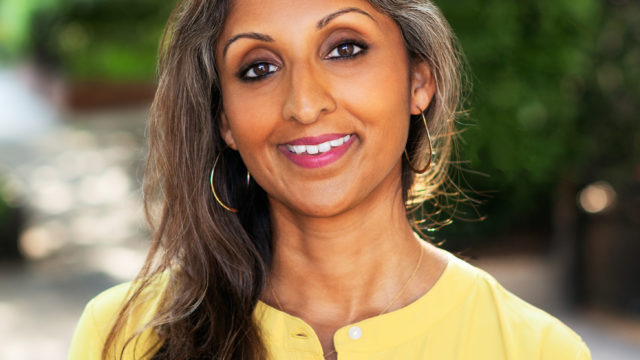 Dr. Sonali Rajan smiling and wearing a yellow shirt