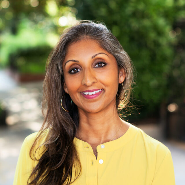 Dr. Sonali Rajan smiling and wearing a yellow shirt