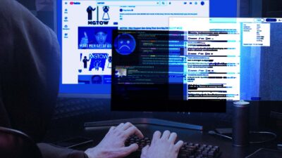 A person wearing a hoodie is typing at their computer. On the screen are blurred screenshots from 4chan