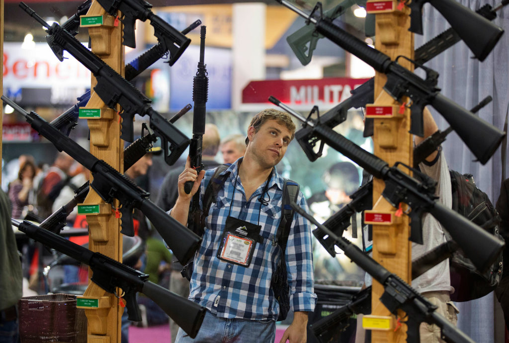 A man looks at a display of rifles at the SHOT Show