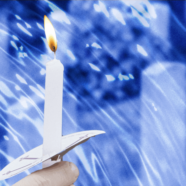 A hand holding a candle with tombstones in the background