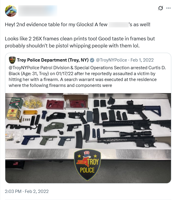 A redacted user quote-tweets the Troy Police Department. Original Tweet: "@TroyNYPolice Patrol Division & Special Operations Section arrested Curtis D. Black (Age:31, Troy) on 01/17/22 after he reportedly assaulted a victim by hitting her with a firearm. A search warrant was executed at the residence where the following firearms and components were." An image, superimposed with the City of Troy Police logo, displays approximately 20 firearms and/or accessories, including ammunition, magazines, and firearms. The redacted user's quote Tweet reads: "Hey! 2nd evidence table for my Glocks! A few [redacted]'s as well! Looks like 2 26X frames clean prints too! Good taste in frames but probably shouldn't be pistol whipping people with them lol."